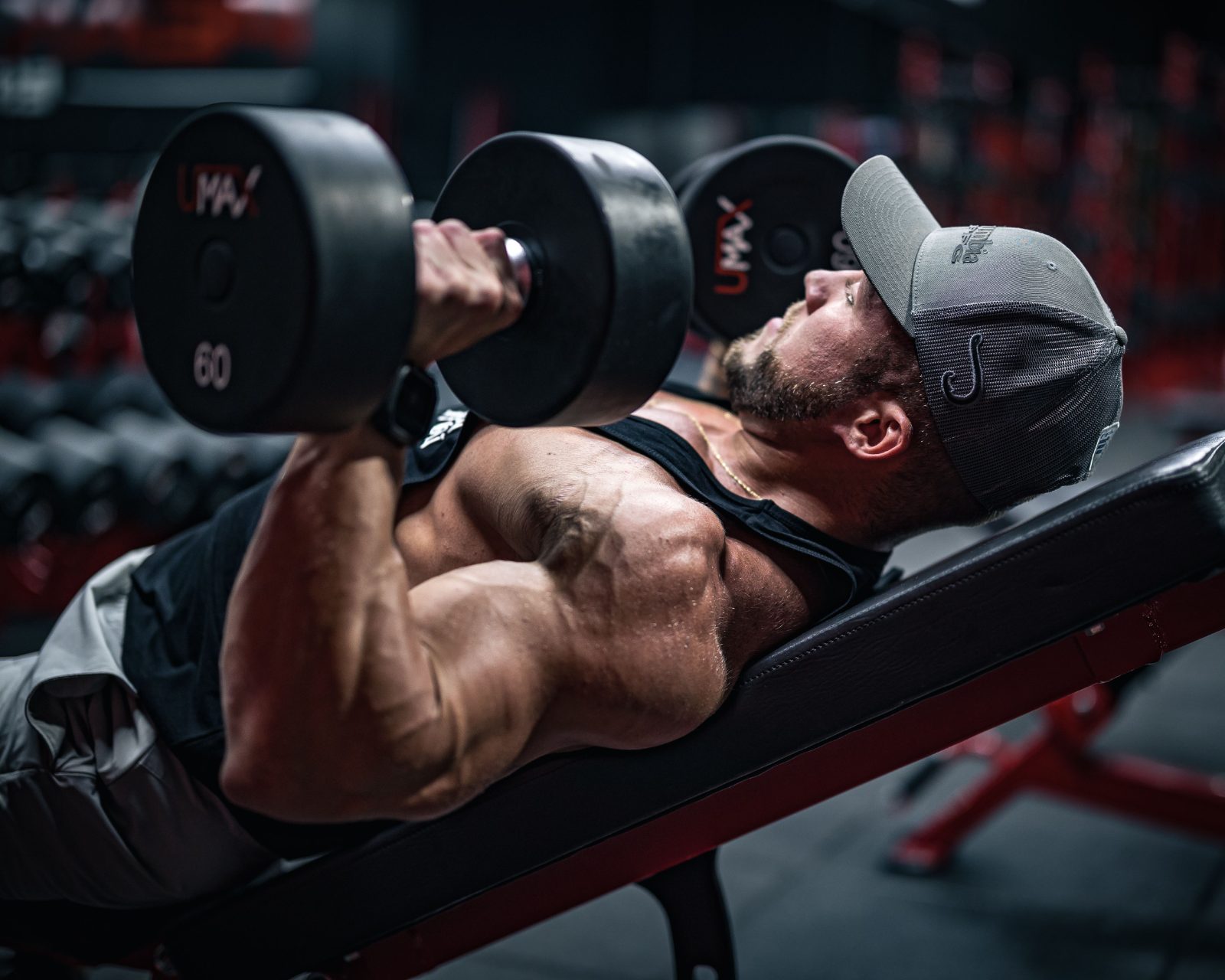 Man pressing dumbbells on a bench in a gym